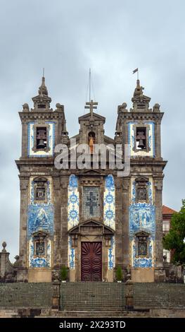 Kirche von San Ildefonso mit einer Fassade, die mit blau-weißen Keramikfliesen bedeckt ist und bei Sonnenaufgang religiöse Motive aufweist, unter grauem und bewölktem Himmel. Porto. Por Stockfoto