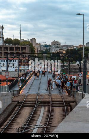 Panoramablick auf die Bahnstrecke von Porto Metro von der Dom-Luis-Brücke in der Abenddämmerung, mit den Lichtern an den Pfählen voller Touristen, die unter einem bewölkten s spazieren gehen Stockfoto