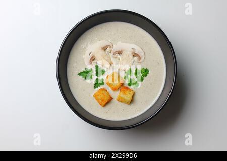 Pilzcremesuppe mit Creme, Croutons und Kräutern auf weißem Holzhintergrund. Köstliche Komfortgerichte, Stockfoto