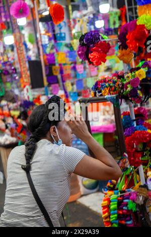 Frau versucht auf Haarband, Day of the Dead Paraphenalia auf dem Jamaica Markt in Mexico City, Mexiko Stockfoto