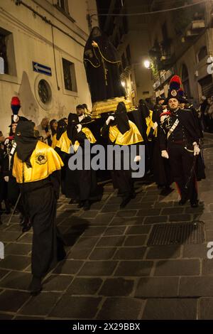 Chieti, Italien - 29. März 2024: Kapuzengläubige tragen die Statue der Madonna in einer Prozession, flankiert von Carabinieri in voller Uniform Stockfoto