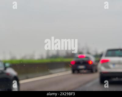 Ein verschwommenes Bild einer belebten Straße mit Autos und einem LKW. Der Regen macht die Windschutzscheibe der Autos und des Lkws nass Stockfoto