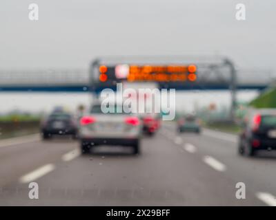 Ein verschwommenes Bild einer befahrenen Autobahn mit Autos und einem LKW. Die Fahrzeuge fahren langsam und der Lkw befindet sich mitten auf der Straße Stockfoto