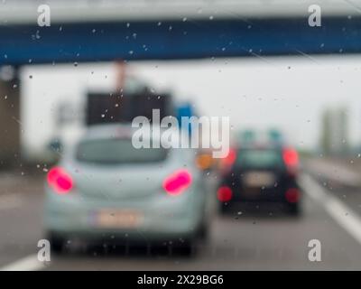 Ein verschwommenes Bild einer belebten Straße mit Autos und einem LKW. Der Regen macht die Windschutzscheibe der Autos und des Lkws nass Stockfoto