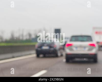 Ein verschwommenes Bild einer belebten Straße mit Autos und einem LKW. Der Regen macht die Windschutzscheibe der Autos und des Lkws nass Stockfoto