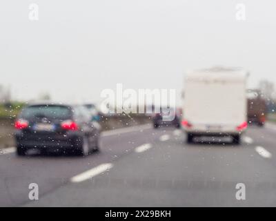 Ein verschwommenes Bild einer belebten Straße mit Autos und einem LKW. Der Regen macht die Windschutzscheibe der Autos und des Lkws nass Stockfoto