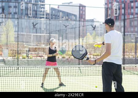 Sportpaare mit Padel-Schlägern, die auf dem Tennisplatz posieren Stockfoto