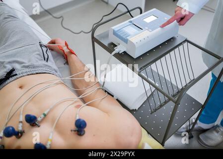 Ein Techniker überwacht einen kardialen Belastungstest mit Elektroden, die an der Brust des Patienten angebracht sind, in einer klinischen Umgebung. Stockfoto