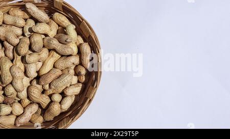 Frische, rohe Erdnüsse, ungeschält in Korb. Erdnüsse mit Schale im Korb auf weißem Hintergrund mit Leerzeichen Stockfoto