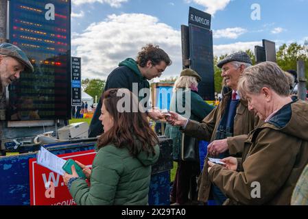 Um die Bookmaker Stände im Feld versammeln sich Menschenmassen, um Wetten auf die Pferde zu platzieren, die bei Parham Point to Point Rennen und dem Familienspaß Tag 2024 fahren Stockfoto