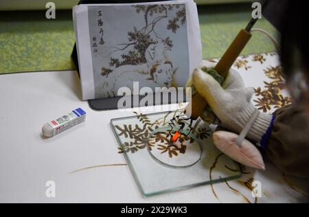 (240421) -- NANYANG, 21. April 2024 (Xinhua) -- Ein Liebhaber der Nanyang-Pyrographie macht ein Kunstwerk der Pyrographie in einer Ausbildungsklasse der Nanyang Pyrography Factory in Nanyang City, Zentralchinas Provinz Henan, 14. März 2024. Die Nanyang Pyrographie, eine traditionelle chinesische Kunst, die aus der westlichen Han-Dynastie (206 v. Chr.–25 n. Chr.) stammt, hat eine über 2.000-jährige Geschichte. Das Handwerk verwendet Werkzeuge mit hoher Temperatur, um Muster auf karbonisierbaren Materialien zu zeichnen, erzeugt visuelle Effekte, die an traditionelle chinesische Gemälde erinnern. Es wurde 2021 als immaterielles Kulturerbe auf nationaler Ebene aufgeführt. Li Zhe, 54, Stockfoto