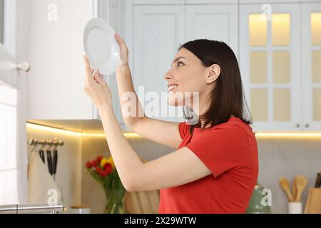 Schöne junge Frau mit Teller in der Küche Stockfoto