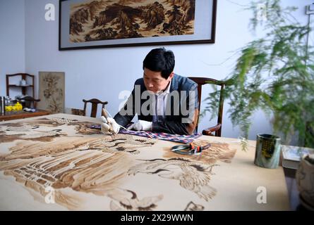 (240421) -- NANYANG, 21. April 2024 (Xinhua) -- Li Zhe macht eine Holzpyrographie in einem Studio der Nanyang Pyrography Factory in Nanyang City, Zentralchinas Provinz Henan, 15. März 2024. Die Nanyang Pyrographie, eine traditionelle chinesische Kunst, die aus der westlichen Han-Dynastie (206 v. Chr.–25 n. Chr.) stammt, hat eine über 2.000-jährige Geschichte. Das Handwerk verwendet Werkzeuge mit hoher Temperatur, um Muster auf karbonisierbaren Materialien zu zeichnen, erzeugt visuelle Effekte, die an traditionelle chinesische Gemälde erinnern. Es wurde 2021 als immaterielles Kulturerbe auf nationaler Ebene aufgeführt. Li Zhe, 54 Jahre alt, ist ein Erben auf Provinzebene Stockfoto