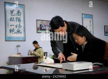 (240421) -- NANYANG, 21. April 2024 (Xinhua) -- Li Zhe führt einen Liebhaber der Nanyang-Pyrographie an, um ein Kunstwerk der Pyrographie in einer Ausbildungsklasse der Nanyang Pyrography Factory in Nanyang, Zentralchinas Provinz Henan, 14. März 2024 zu erstellen. Die Nanyang Pyrographie, eine traditionelle chinesische Kunst, die aus der westlichen Han-Dynastie (206 v. Chr.–25 n. Chr.) stammt, hat eine über 2.000-jährige Geschichte. Das Handwerk verwendet Werkzeuge mit hoher Temperatur, um Muster auf karbonisierbaren Materialien zu zeichnen, erzeugt visuelle Effekte, die an traditionelle chinesische Gemälde erinnern. Es wurde 202 als immaterielles Kulturerbe auf nationaler Ebene aufgeführt Stockfoto