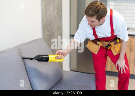 Man-Reinigungspersonal Hand in schützenden Gummihandschuh Reinigung Sofa mit professionell Extraktionsverfahren. Anfang Frühling regelmäßige Reinigung Stockfoto