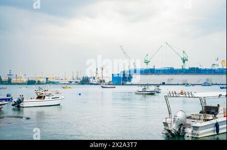 Das große Schiff legte friedlich im belebten Hafen an. Wichtige Rolle der Seeverkehrslogistik und des Seeverkehrs. Handelsschiffe im Hafen, die die globale Schifffahrt zeigen Stockfoto