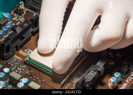 Mann Hand in weißen antistatischen Handschuhen, die den Computerprozessor installieren Stockfoto
