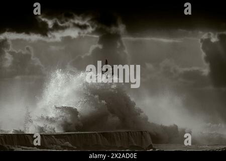 Grossen Sturm wave gegen Leuchtturm von Vila do Conde, nördlich von Portugal (Enhanced sky), bei Sonnenuntergang Stockfoto
