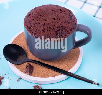 Der Mugcake ist in der Mikrowelle. Hausgemachter Cupcake in einer Tasse ist auf einem Teller. Stockfoto