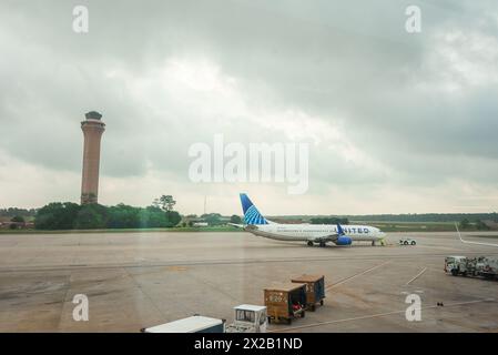 Charlotte, USA 14 04 21, United Airlines-Flugzeug parkte auf der Landebahn am Charlotte Douglas International Airport mit dem Kontrollturm im Hinterland Stockfoto