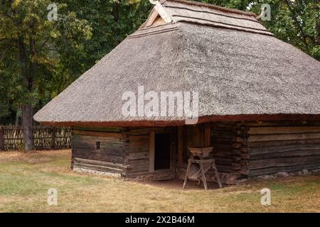 Ein Holzhaushalt aus Baumstämmen und Strohdach in einem alten Bauernhof in Litauen. Stockfoto