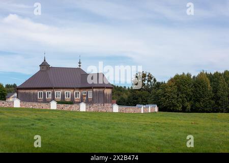 Eine alte hölzerne katholische Kirche mit einem Steinzaun in der Nähe des Waldes. Litauen Rumsiskes. Stockfoto