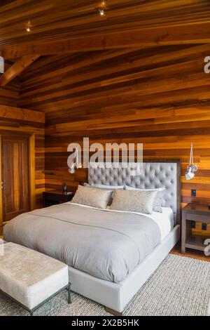 King size Bett mit grauen gepolsterten panel Kopfteil, osmanischen und Holz- Ende Tabellen im Hauptschlafzimmer mit grauen Nuancen Wolldecke und Ipe holz Boden, Innen, l Stockfoto