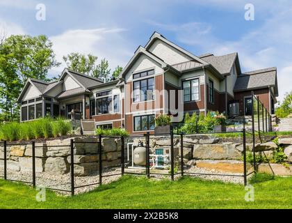 Rückansicht von zeitgenössischem Naturstein und braun gebeiztem Holz und Zedernschindeln bekleidet luxuriöses Bungalow-Haus im Sommer, Quebec, Kanada, Norden Stockfoto