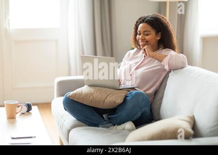 Glückliche Frau, die zu Hause am Laptop arbeitet Stockfoto