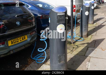 Elektroautos – ein BMW i3 und ein Tesla angeschlossen und geladen – an einer EV-Ladestation des öffentlichen Netzwerks von Source London. London, England Stockfoto