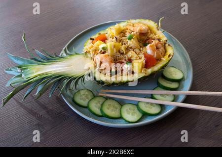 Ananas-gebratener Reis ist ursprünglich thailändischer Herkunft. Hier ist eine hausgemachte Version mit einer ausgehöhlten Ananas mit Ananasstücken, Garnelen und Tomaten Stockfoto