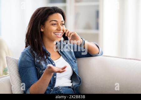 Frau, die auf der Couch sitzt und auf dem Handy spricht Stockfoto