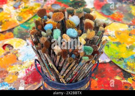 Blick auf in einem Gefaess stehende Malpinsel am 26.03.2024 in einem Malstudio, Atelier, in Goehren-Lebbin, Mecklenburg Vorpommern. Im Hintergrund sind verschiedene Malpaletten zu sehen. Ansicht von Malpinseln in einer Box am 26. März 2024 in einem Malerstudio in Goehren-Lebbin, Mecklenburg-Vorpommern. Im Hintergrund sind verschiedene Malpaletten zu sehen. Suche: Deutschland Kunst Kultur Hobby Freizeit Malen Malkunst Beschaeftigung Farben Pinselset Farbpalette Farbreste Kuenstlermaterialien Flachpinsel Innenaufnahme Kreativitaet Malfarben Malutensilien Malatelier Kun Stockfoto