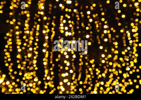 Bokeh-Highlights. Goldene und gelbe Farbe blinkt im Dunkeln. Festlicher Hintergrund. Unscharfe Unschärfe. Dekoration der Straßen der Stadt. Viele gelbe Kugeln. Mann Stockfoto