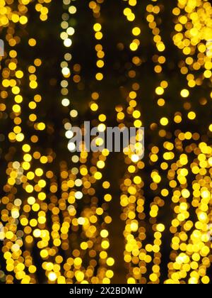 Bokeh-Highlights. Goldene und gelbe Farbe blinkt im Dunkeln. Festlicher Hintergrund. Unscharfe Unschärfe. Dekoration der Straßen der Stadt. Viele gelbe Kugeln. Mann Stockfoto