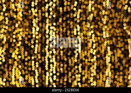 Bokeh-Highlights. Goldene und gelbe Farbe blinkt im Dunkeln. Festlicher Hintergrund. Unscharfe Unschärfe. Dekoration der Straßen der Stadt. Viele gelbe Kugeln. Mann Stockfoto