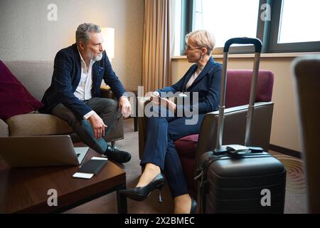 Seitenansicht eines seriösen Geschäftsmannes und einer Geschäftsfrau, die im Hotelzimmer sprechen Stockfoto