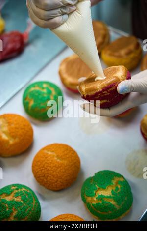 Baker füllt Choux au Craquelin mit Kondensmilch auf Stockfoto