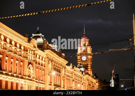 Die legendäre Flinders Street Station, beleuchtet von leuchtendem orangefarbenem Licht gegen den Nachthimmel, mit ihrem unverwechselbaren Uhrturm, der ein zeitloses Si erzeugt Stockfoto