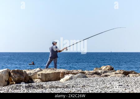 Ein Mann, der am Strand von Nizza, Cote d'Azur, Frankreich, angelt Stockfoto