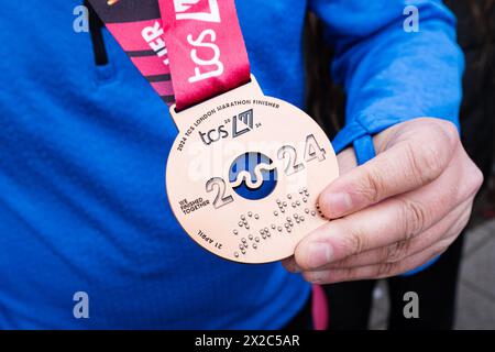 London, Großbritannien. April 2024. Ein Finisher des Marathons zeigt seine Medaille der Leistung. Über 50.000 Läufer nahmen am London Marathon 2024 Teil. Quelle: SOPA Images Limited/Alamy Live News Stockfoto