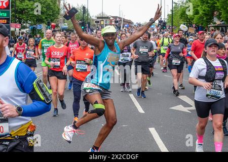 London Marathon 2024: Weibliche Läuferin tanzt mit breiten Armen auf der Route des 44. London Marathon Stockfoto