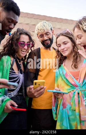 Seitenansicht multirassische lächelnde Gruppe junge Generation z Ziegelwand mit Telefonen im Freien. Stockfoto