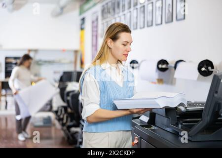 Der Techniker wechselt das Papier auf der Plottermaschine des Druckers Stockfoto