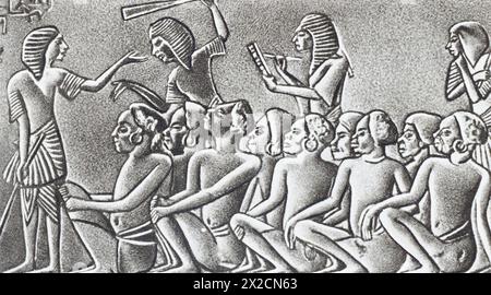 Altägyptische Schriftgelehrte kopieren gefangengenommene Sklaven. Relief aus dem Grab von Horemheb, 2. Jahrtausend v. Chr. Foto aus der Mitte des 20. Jahrhunderts. Stockfoto