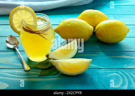 Frische reife Zitronen mit Glas Zitronensaft auf bunten türkis blau lackierte Holzplatten Stockfoto