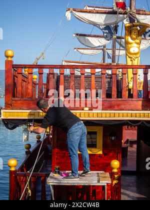 Ein Vergnügungsboot, das aussieht wie ein Piratenschiff. Ein Arbeiter arbeitet an Deck. Industrie im Resort. Vorbereitung auf die Saison Stockfoto