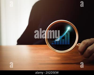 Geschäftsanalytikdiagramm, digitales Wachstumsdiagramm-Symbol in runder Linse aus goldener Lupe in der Hand eines Geschäftsmannes auf dunklem Hintergrund. Trendsuche, Stockfoto