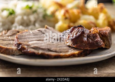 Scheiben von geröstetem Hals mit Kartoffeln und Reis auf einem Teller - Nahaufnahme. Stockfoto