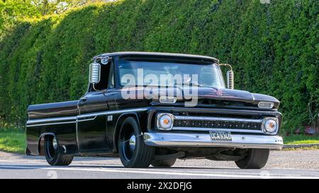 Bicester, UK - 21. April 2024: 1966 schwarzer Chevrolet klassischer Pickup-Truck, der auf einer britischen Straße fährt Stockfoto